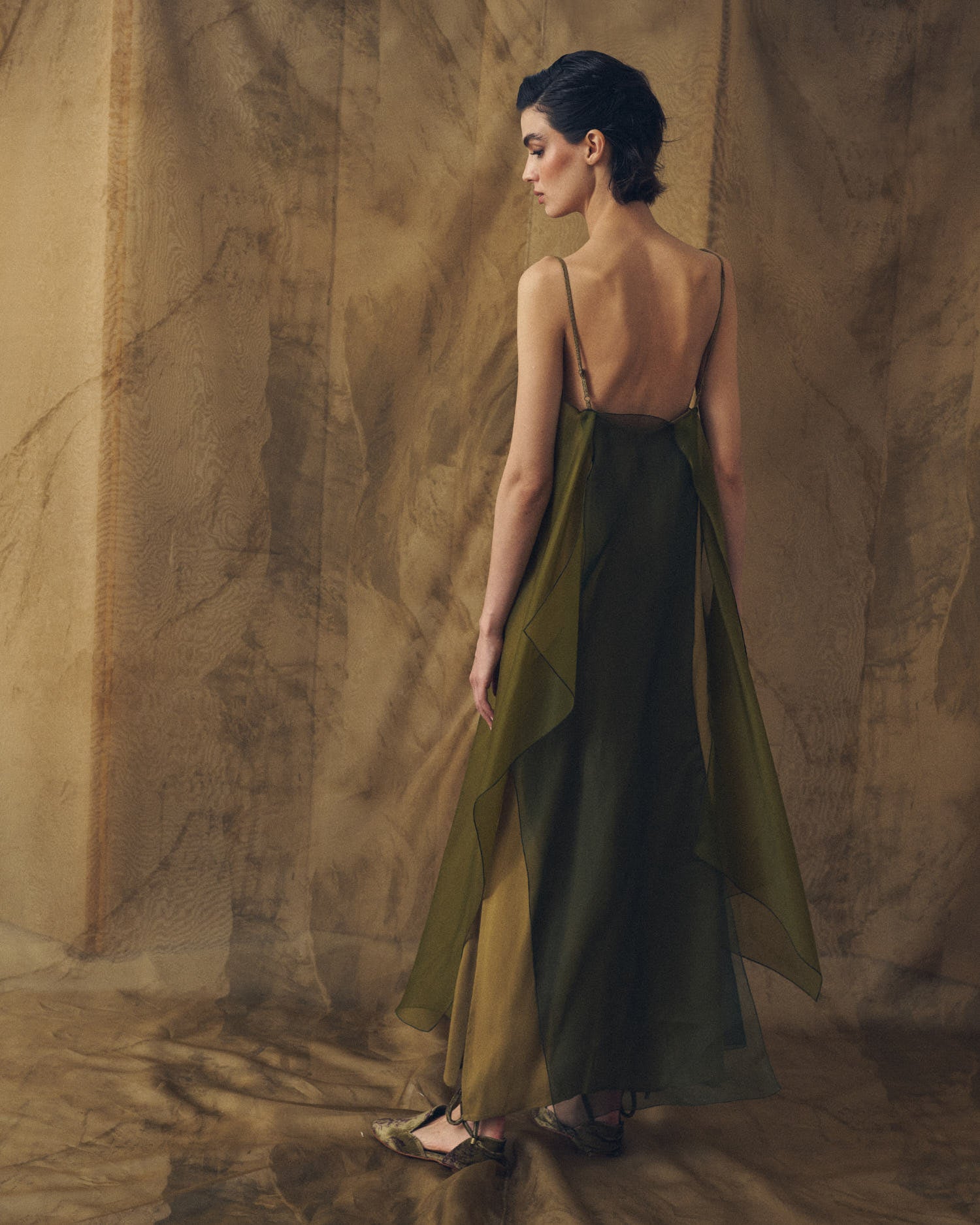 Three-quarter back view of model wearing the open-back Panarea long organza dress in hunting green by T.ba