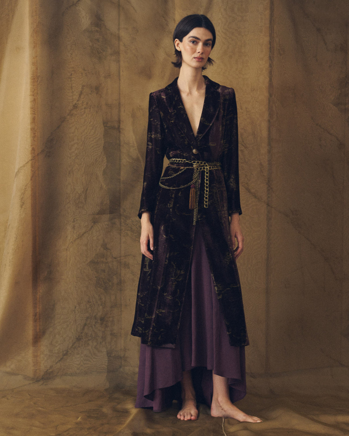 Full-length view of model wearing the Powin Bolero long linen skirt in grape purple styled with a long velvet coat by T.ba