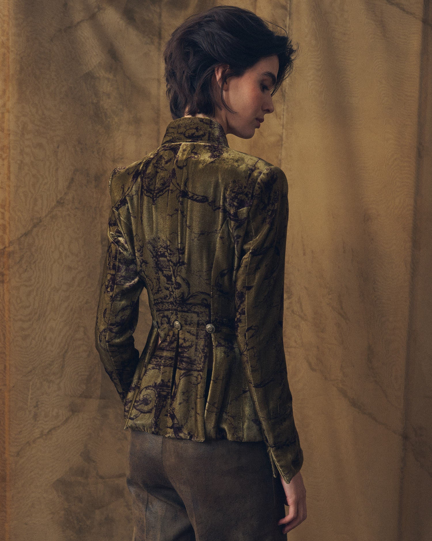 Back view of model wearing the tailored Sam silk velvet jacket in print mocca with pleated hem details by T.ba