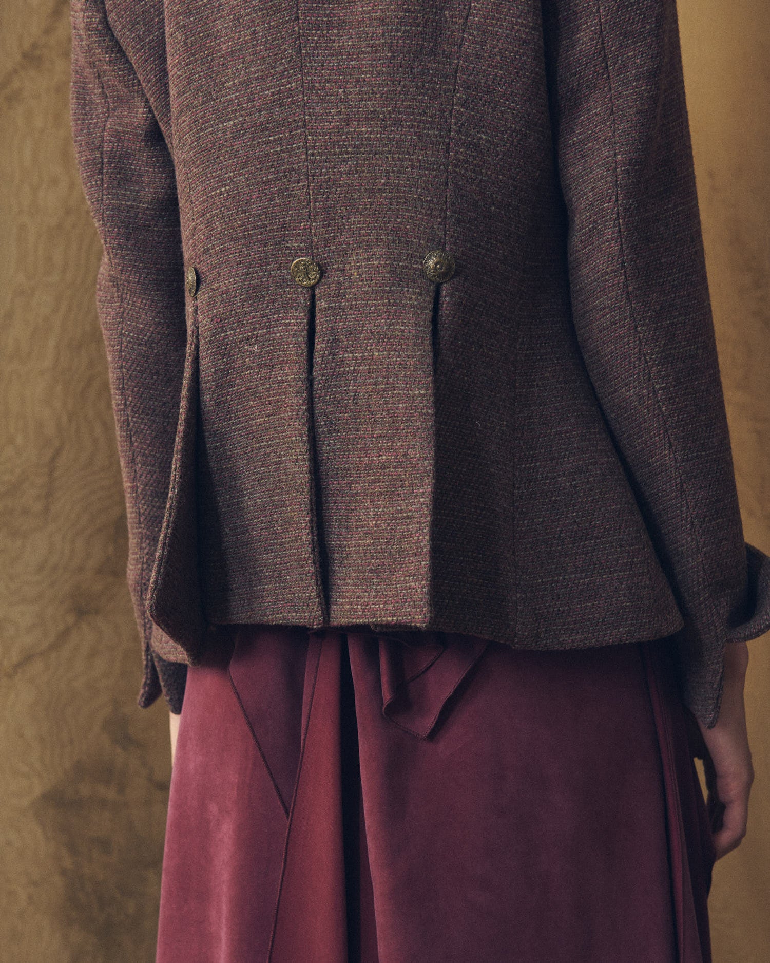Close-up back view of the Sam brown tweed jacket featuring structural pleats and decorative metal buttons by T.ba