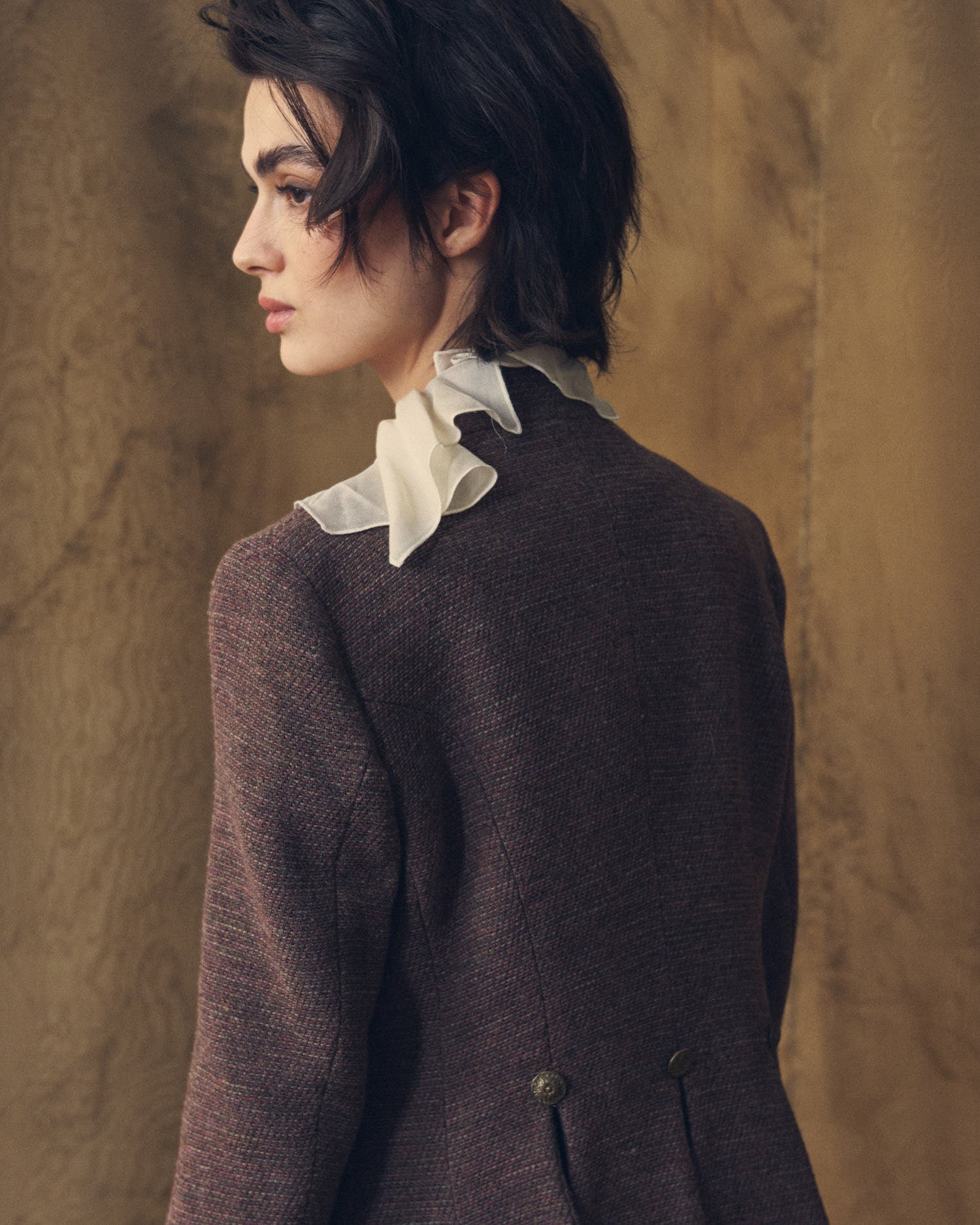 Side profile view of model wearing the tailored Sam brown tweed jacket with standing collar by T.ba