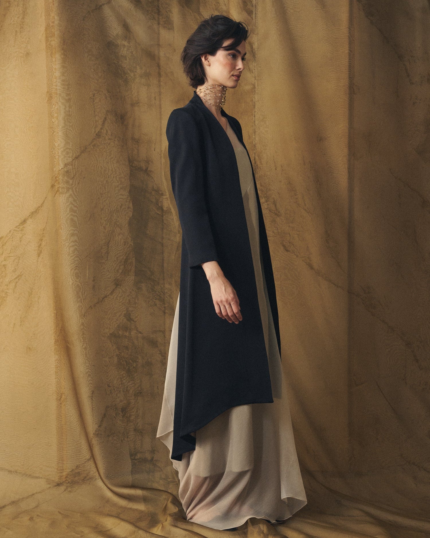 Side profile view of women's Black Sharkskin Ginebra long tailored coat in wool by T.ba