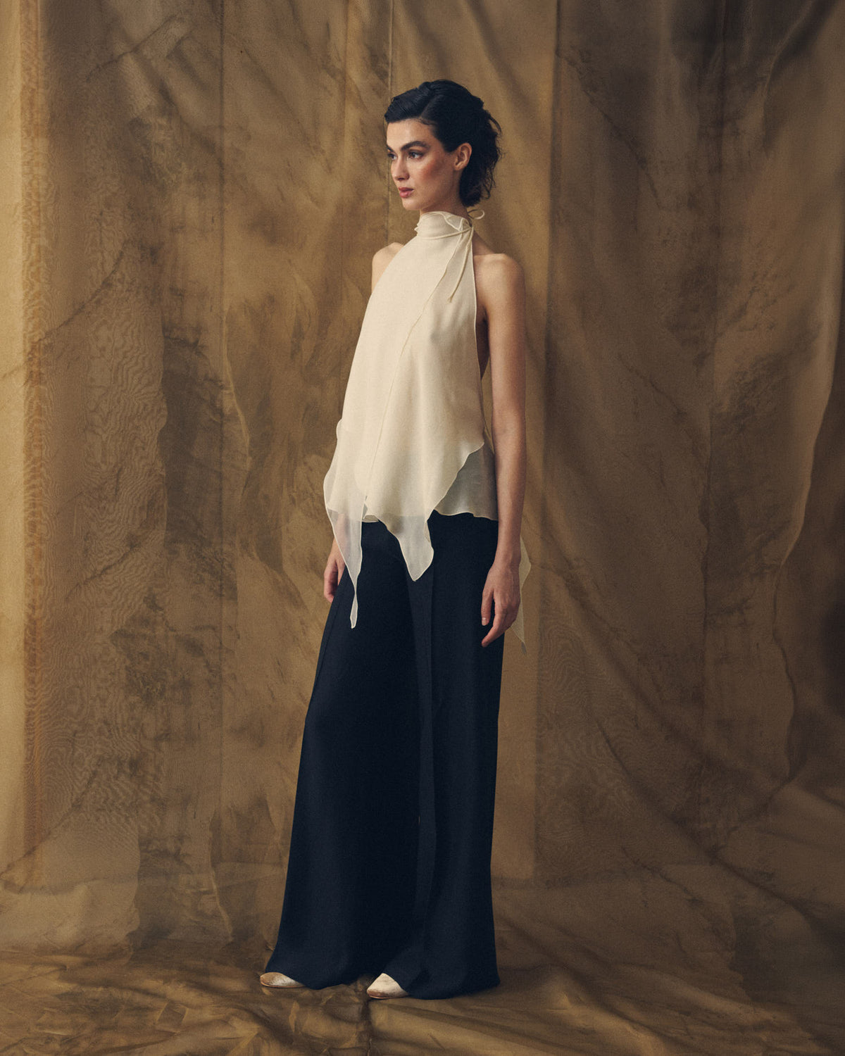 Three-quarter view of model showcasing the fluid drape of the high-waisted Sharkskin Maxi Pants in black for women by T.ba