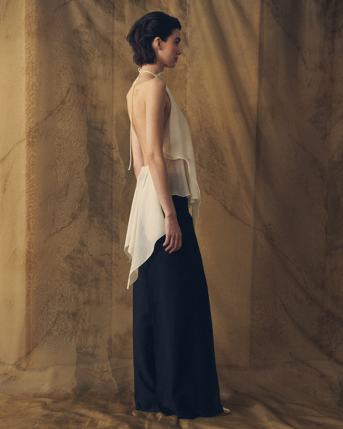 Profile side view of model wearing the elegant high-rise Sharkskin Maxi Pants in black for women by T.ba