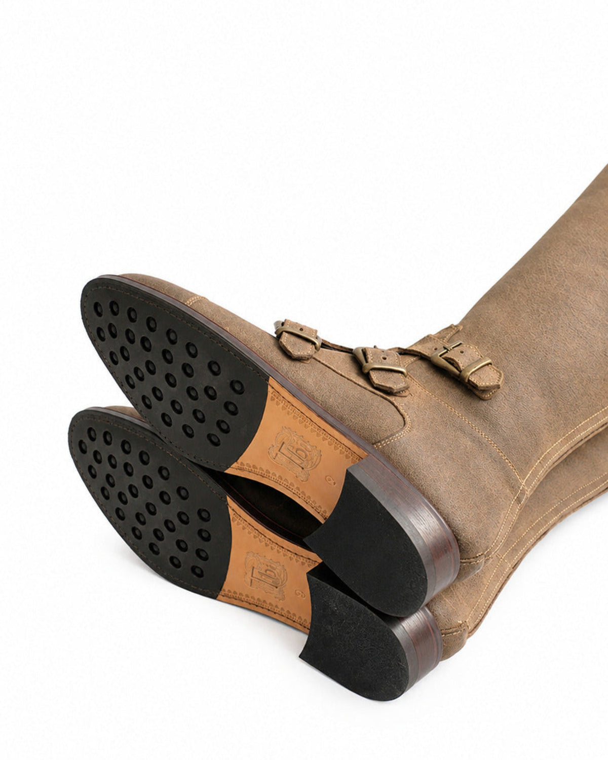 Bottom view highlighting rubber studded grip leather soles and engraved logo on beige suede Buckle Boots T.ba