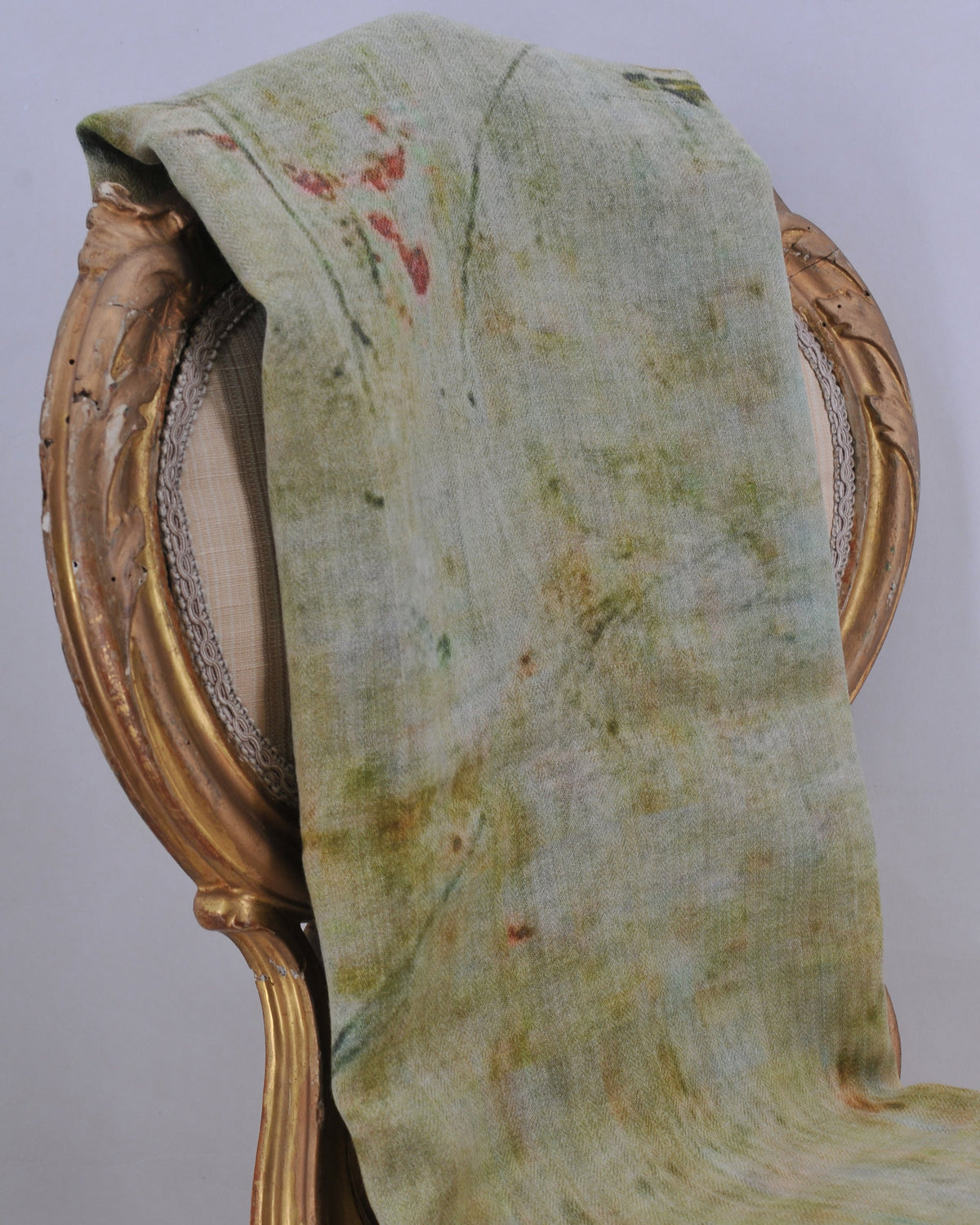 Studio display of Greta shawl draped over vintage chair showing subtle green and floral pattern for women T.ba