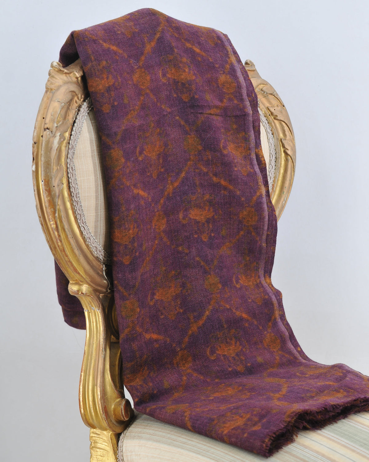 Studio shot of Versailles wool shawl draped over classic chair displaying deep purple wool with gold damask print for women T.ba