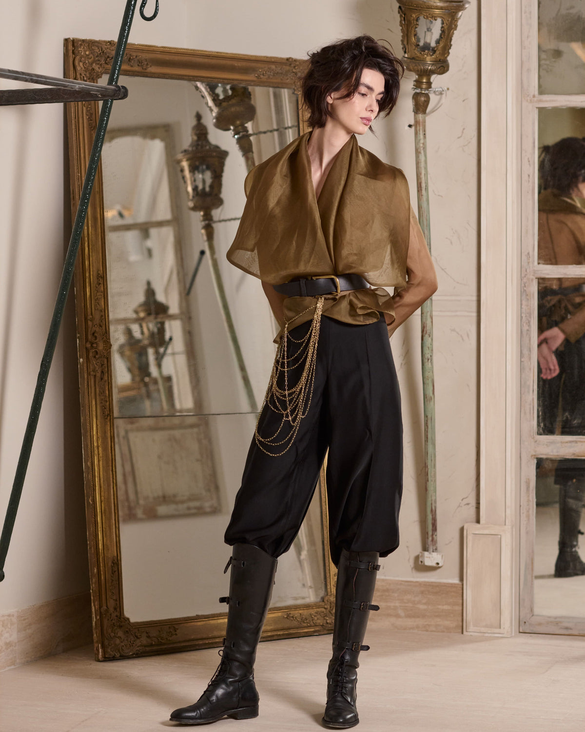 Studio full-length view of translucent Organza Alina jacket in toffee styled with wide belt, black pants, and high boots for women T.ba