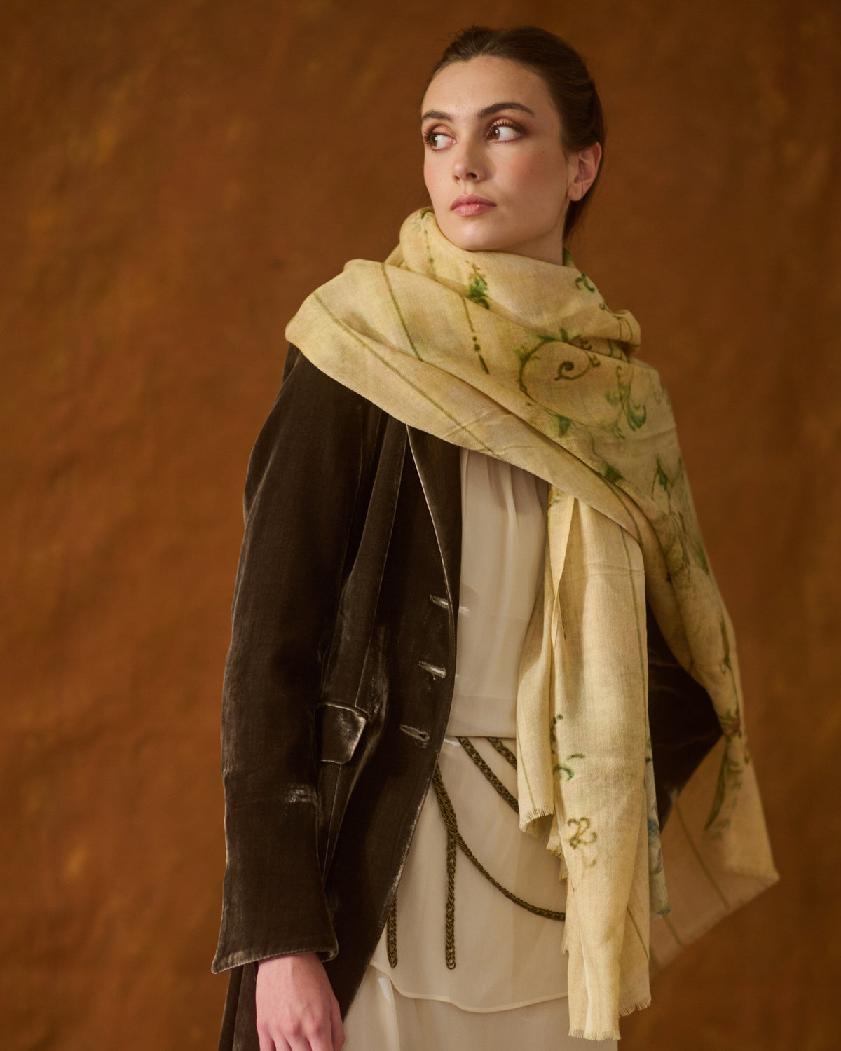 Model wearing cream printed Fiore shawl wrapped around neck styled with velvet coat for women T.ba