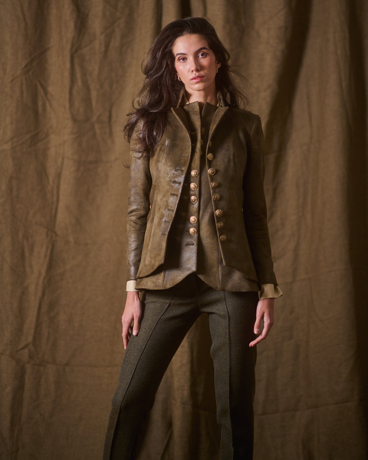 Full-length portrait view of model wearing khaki leather Gnu Baltea jacket with golden buttons for women T.ba