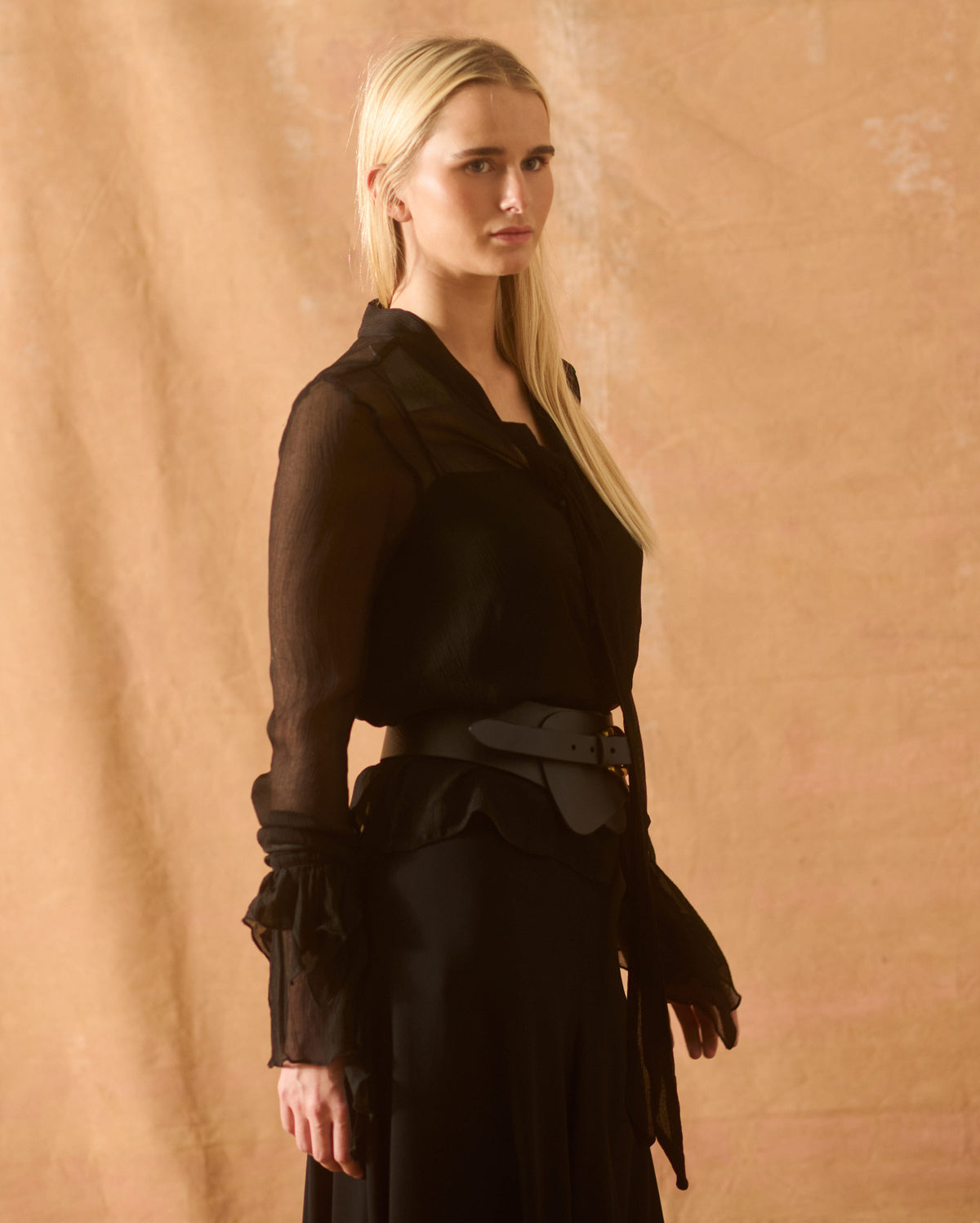 Three-quarter profile view of model wearing the structured wide black leather Toscana Belt fitted at the waist for women by T.ba