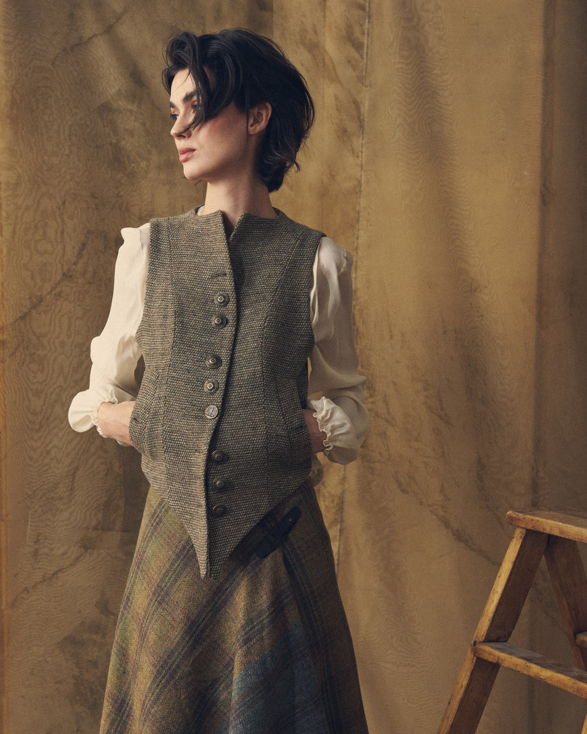 Side profile view of the Tweed Knit Baltea Vest in taupe wool tweed with hand-pockets worn over a silk blouse by T.ba.