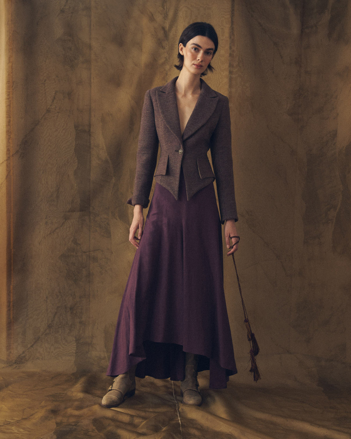 Full length view of model wearing the tailored Verdi Tweed Knit jacket in grape paired with long purple skirt by T.ba