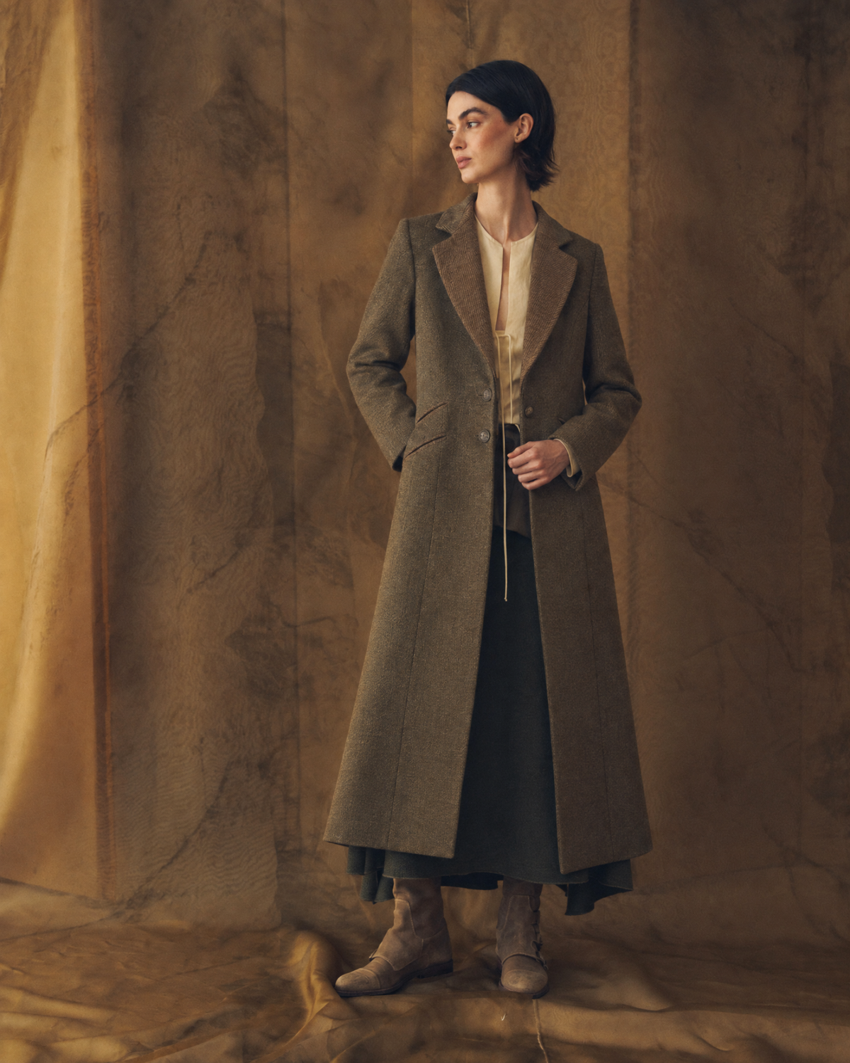 Full length side profile view of model wearing the fitted Tweed Lancelot Combi Coat in brown wool tweed for women by T.ba