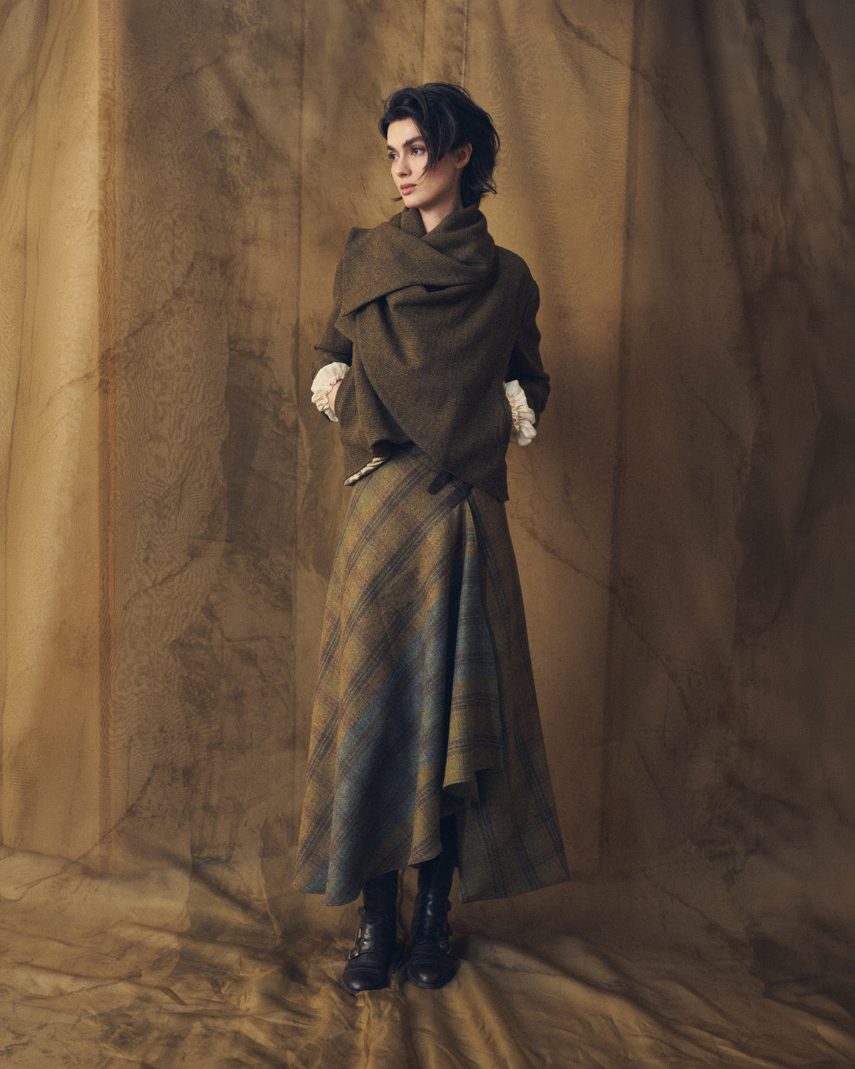 Full length view of model showcasing the asymmetric hemline of the Tweed Lancelot Skirt Mix in olive green tweed for women by T.ba