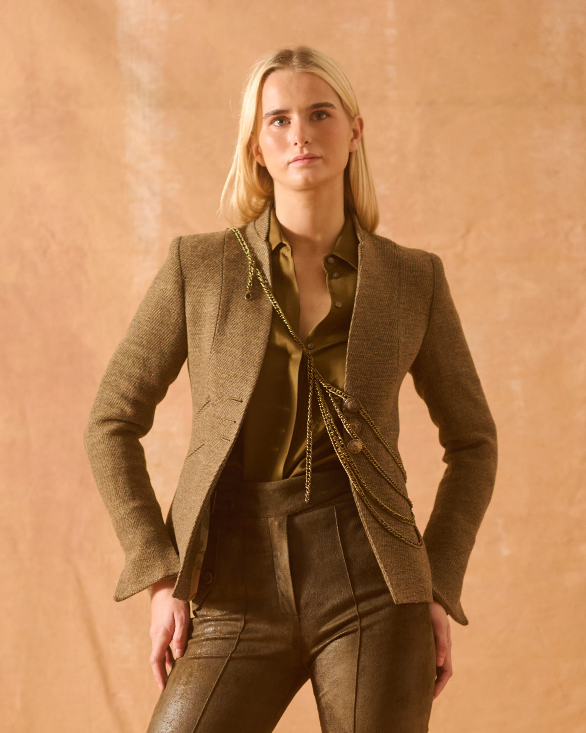 Front medium view of model wearing the tailored Tweed Sam Jacket in brown wool tweed featuring decorative metallic chain details for women by T.ba