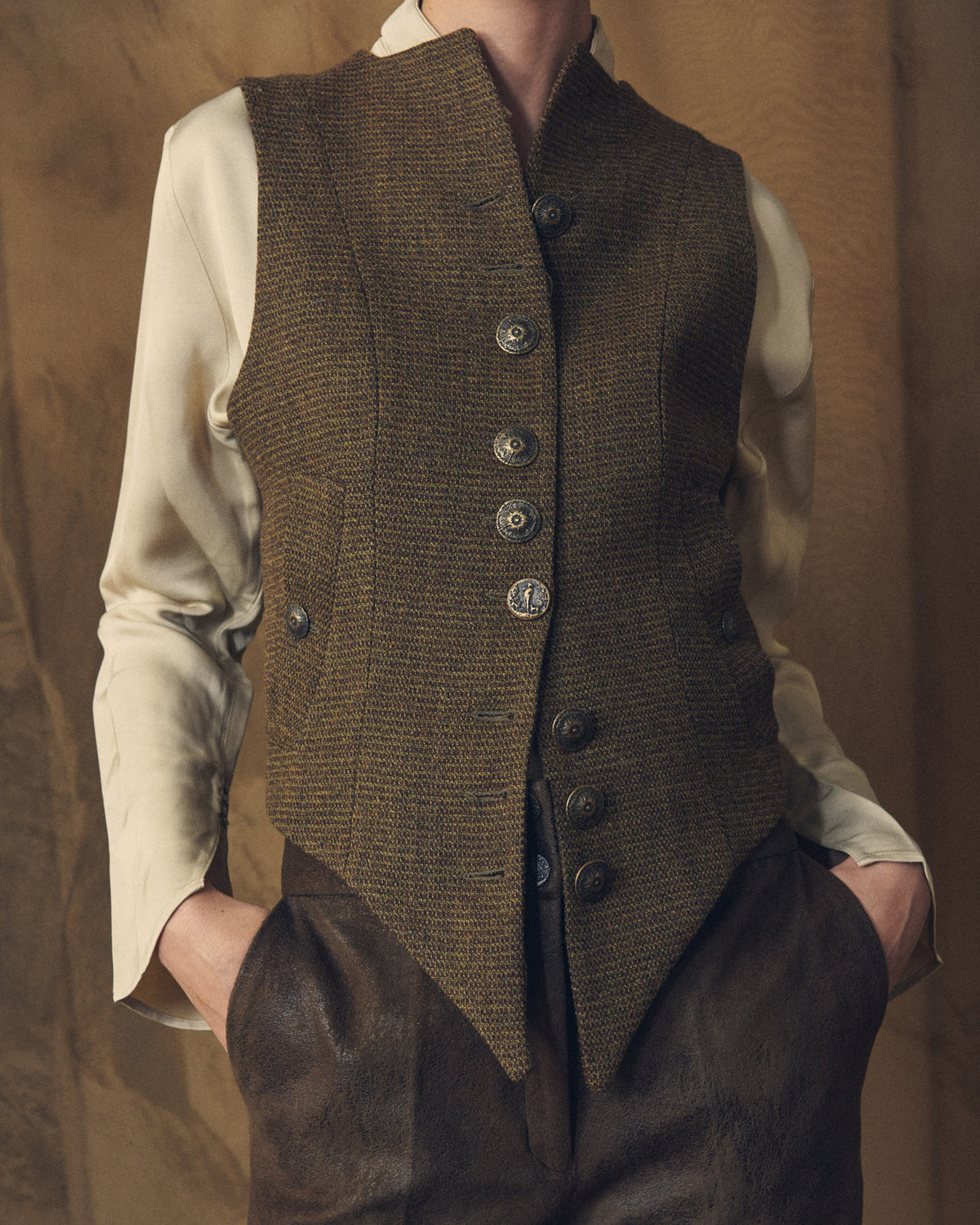 Close-up view highlighting the brown tweed wool texture and ornamental metal buttons of the Tweed Short Baltea Vest for women by T.ba