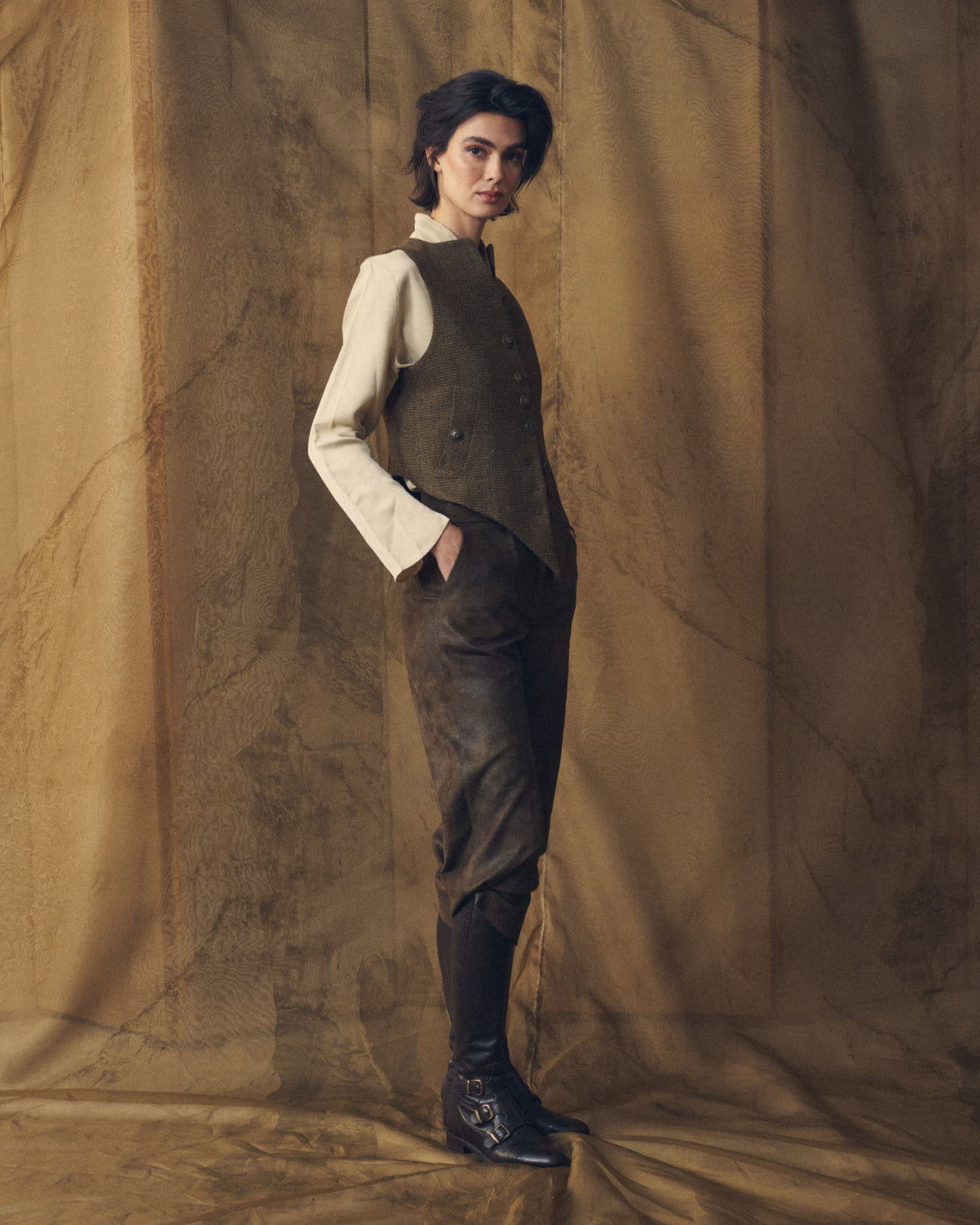 Full length side profile view of model wearing the Tweed Short Baltea Vest in brown tweed paired with a cream shirt for women by T.ba