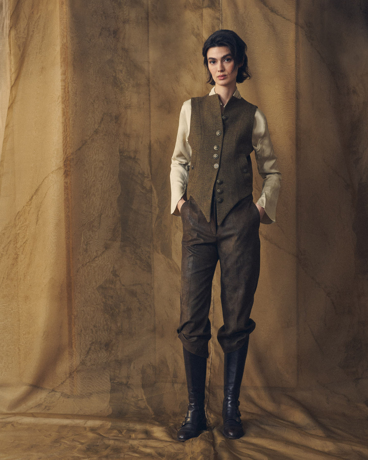 Full length front view of model wearing the fitted Tweed Short Baltea Vest in brown wool tweed with metallic buttons for women by T.ba