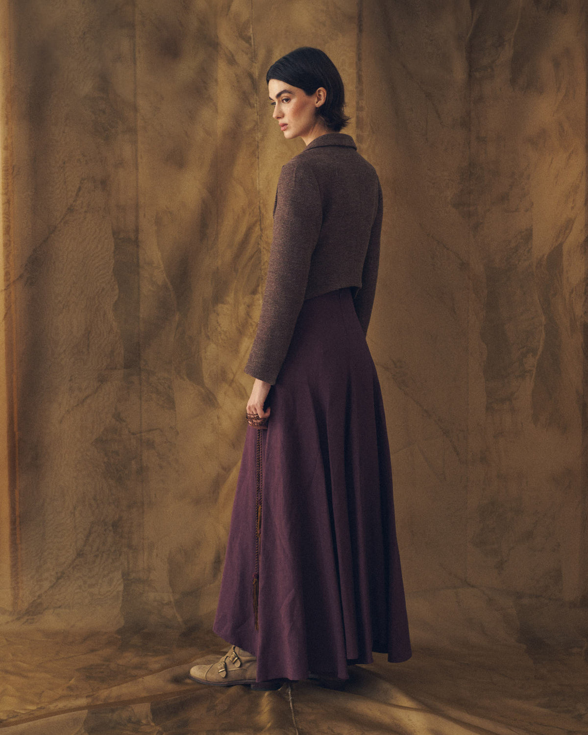 Three-quarter rear view of model wearing the cropped Verdi Tweed Knit jacket in grape wool weave by T.ba