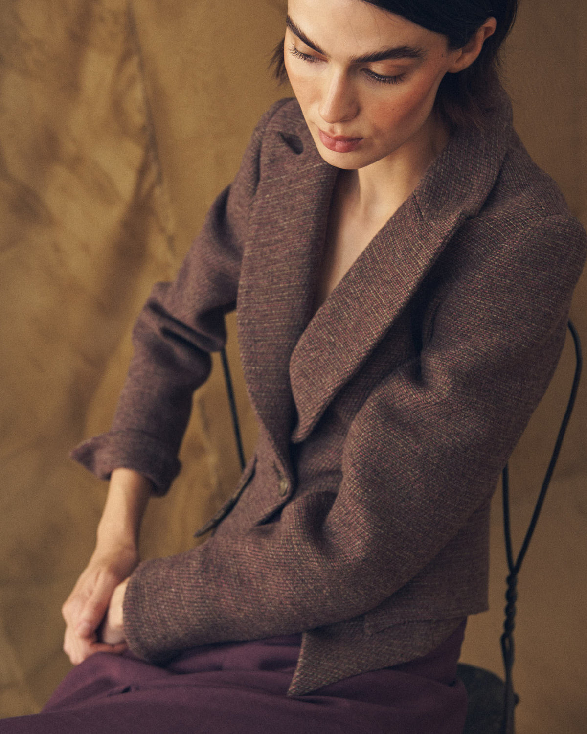High angle shot of model seated wearing the cropped Verdi Tweed Knit jacket in grape weave texture by T.ba